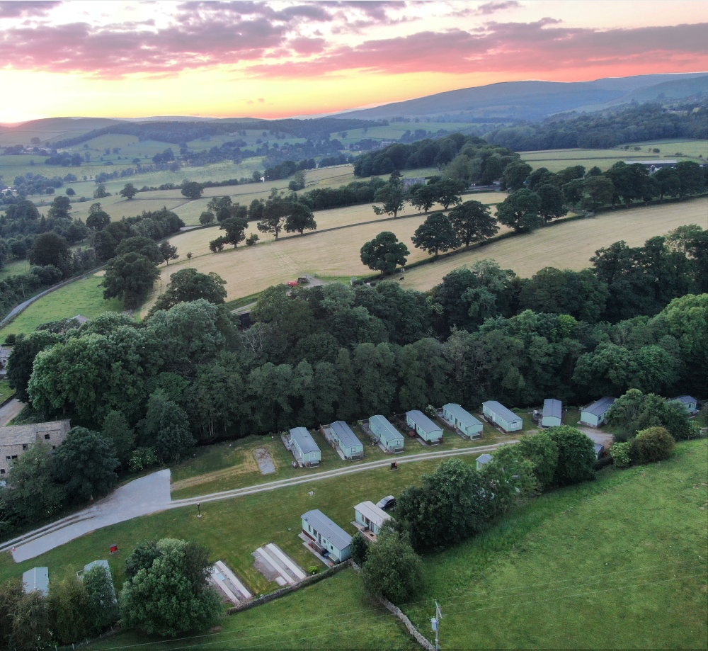An aerial view of Beamsley Mill set against the rolling hills near Bolton Abbey and a beautiful skyline on a summer evening.
